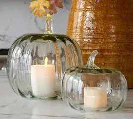 A couple of glass pumpkins with candles inside