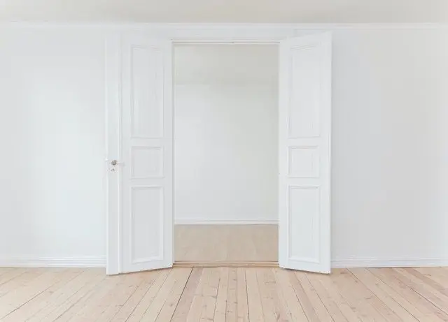 A room with two doors open and the floor is empty.