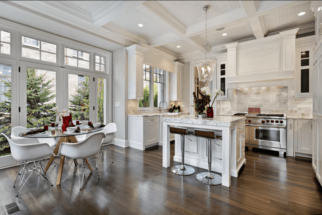 A kitchen with white cabinets and wooden floors.