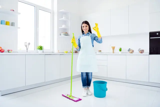 a woman cleaning the kitchen with a mop and bucket