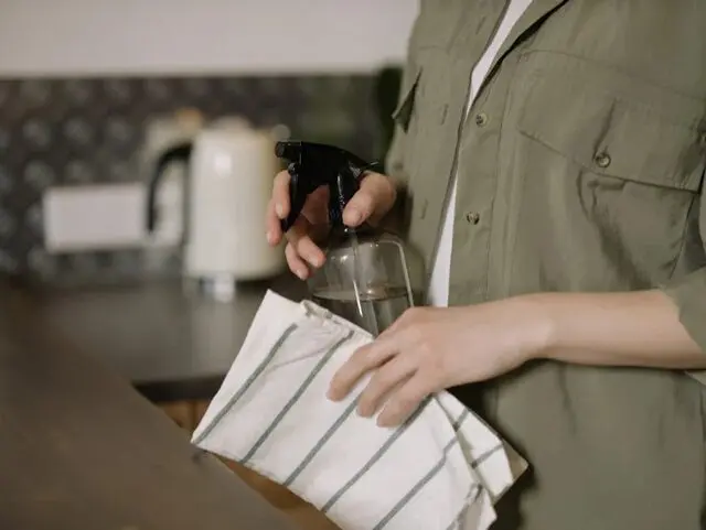 a woman's hands with a spray bottle and a towel