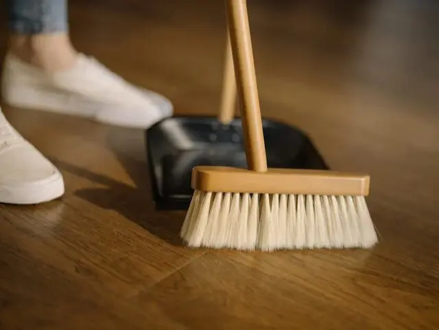 sweeping wood floors with a broom and dustpan