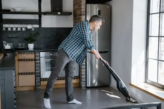 a man tidying by vacuuming a room