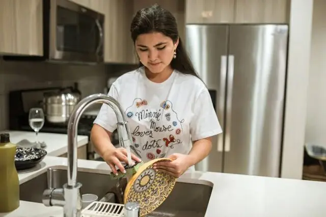 a woman washing dishes while cleaning the kitchen