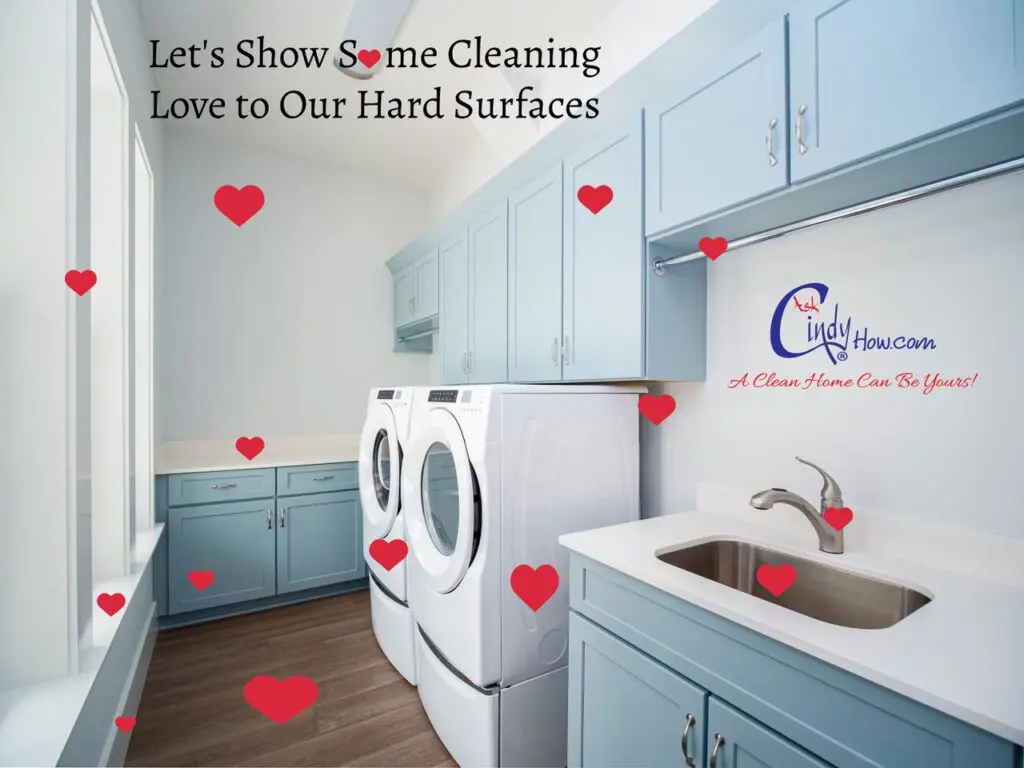 A residential laundry room with washer, dryer, painted cabinets with drawers, a window, wood flooring and a sink.