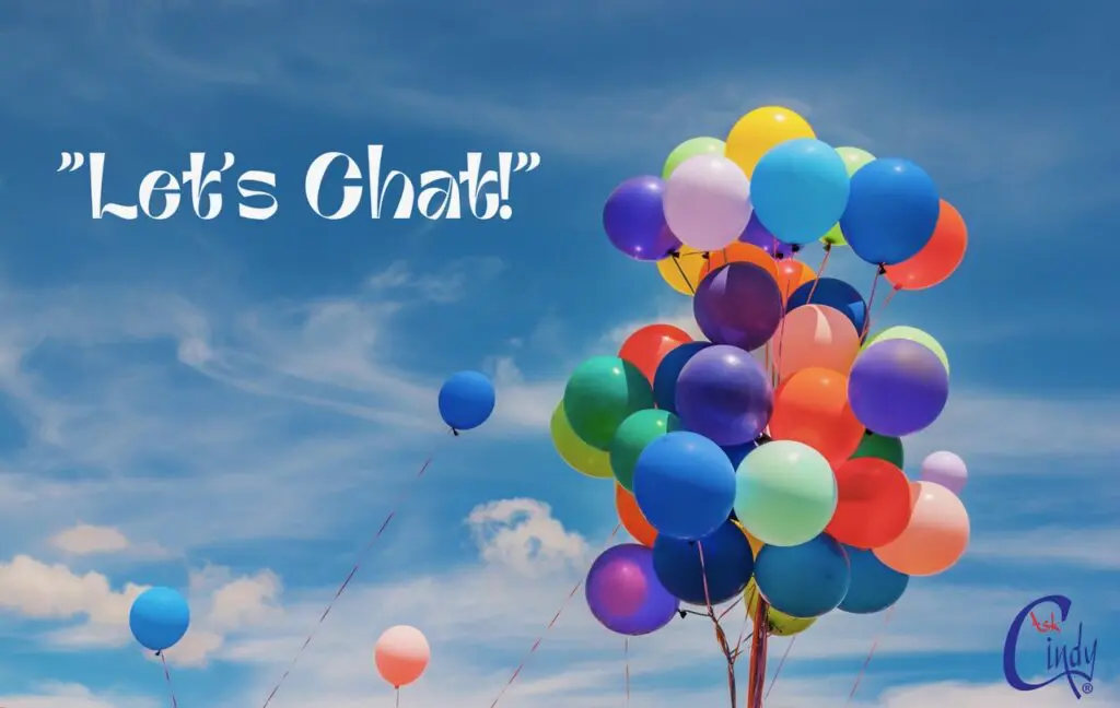 A bunch of Colorful balloons ascending into the blue sky passing white fluffy clouds.
