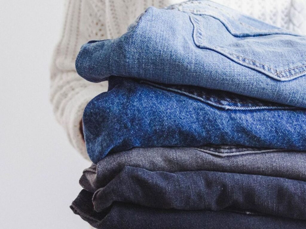 a person carrying several pairs of folded jeans
