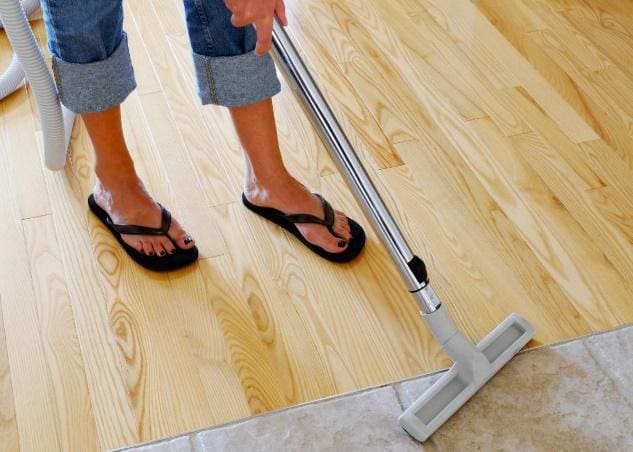 A person in flip flops standing on the floor with their feet up.