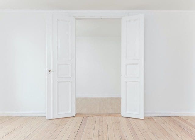 A room with two doors open and the floor is empty.