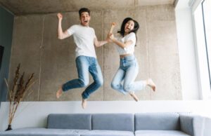 Joyful couple springing off their couch in excitement