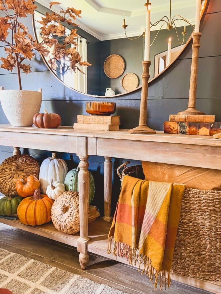 a family room with a mirror and a sidebar decorated with autumn leaves and heirloom pumpkins
